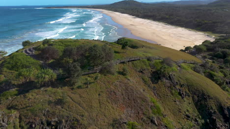 Cinematic-drone-shot-flying-over-rock-outcropping-lowering-to-the-sandy-shore-at-Cabarita-Beach-Australia