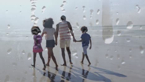Animation-of-happy-african-american-family-walking-at-beach-holding-hands-over-droplets