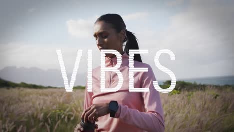 Animation-of-the-word-vibes-written-in-white-over-woman-hiking-in-countryside-drinking-water