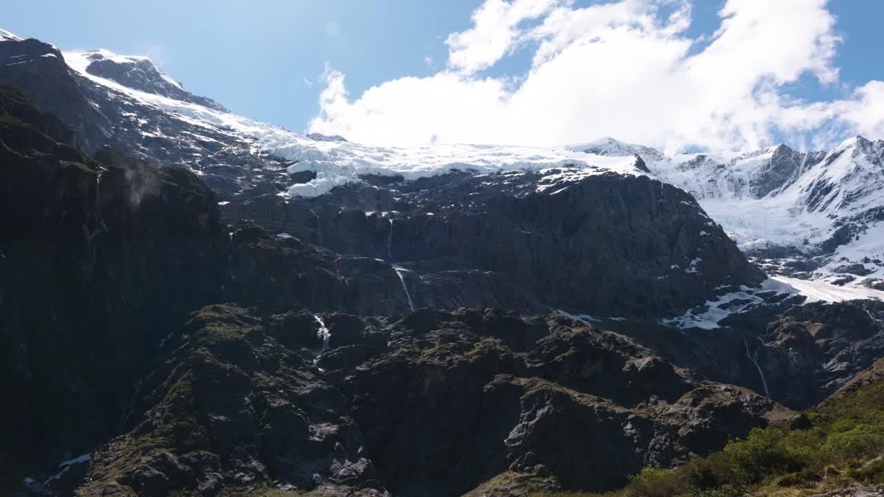 Wide view of snow covered mountains and glacier on a sunny day at Rob Roy Glacier, Wanaka, New Zealand.
