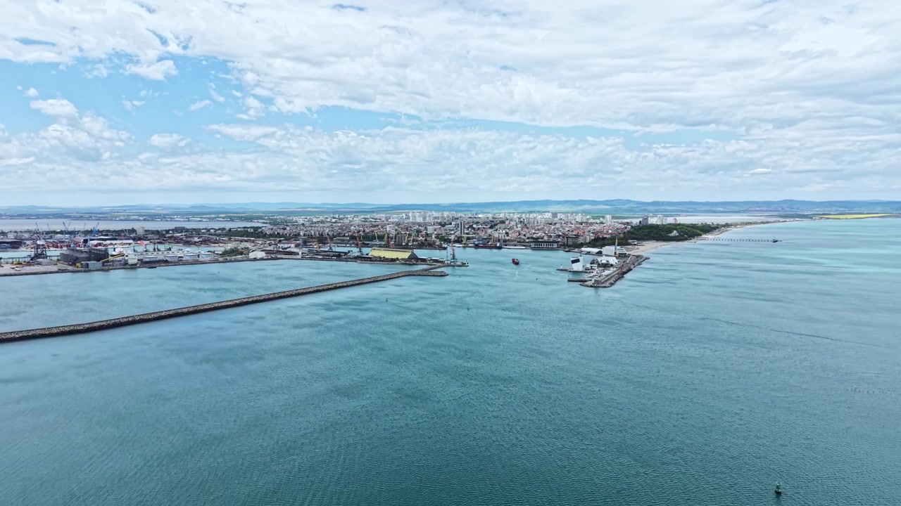 Vista di una città portuale sul mare in una giornata di sole con nuvole in cielo e barche visibili nel porto e sull'acqua