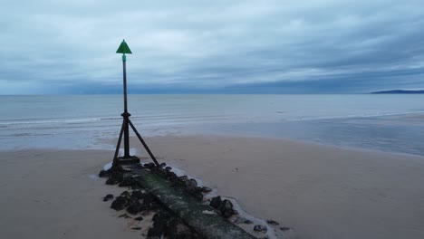 Coastal tide marker aerial view low slow push in right across moody overcast low tide seaside beach