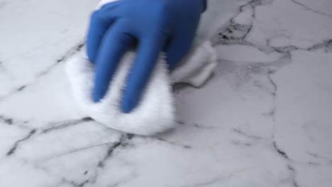 limpieza de una encimera de mármol con guantes y una toalla