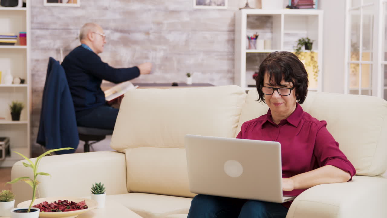 Elderly Woman Using Laptop on Couch