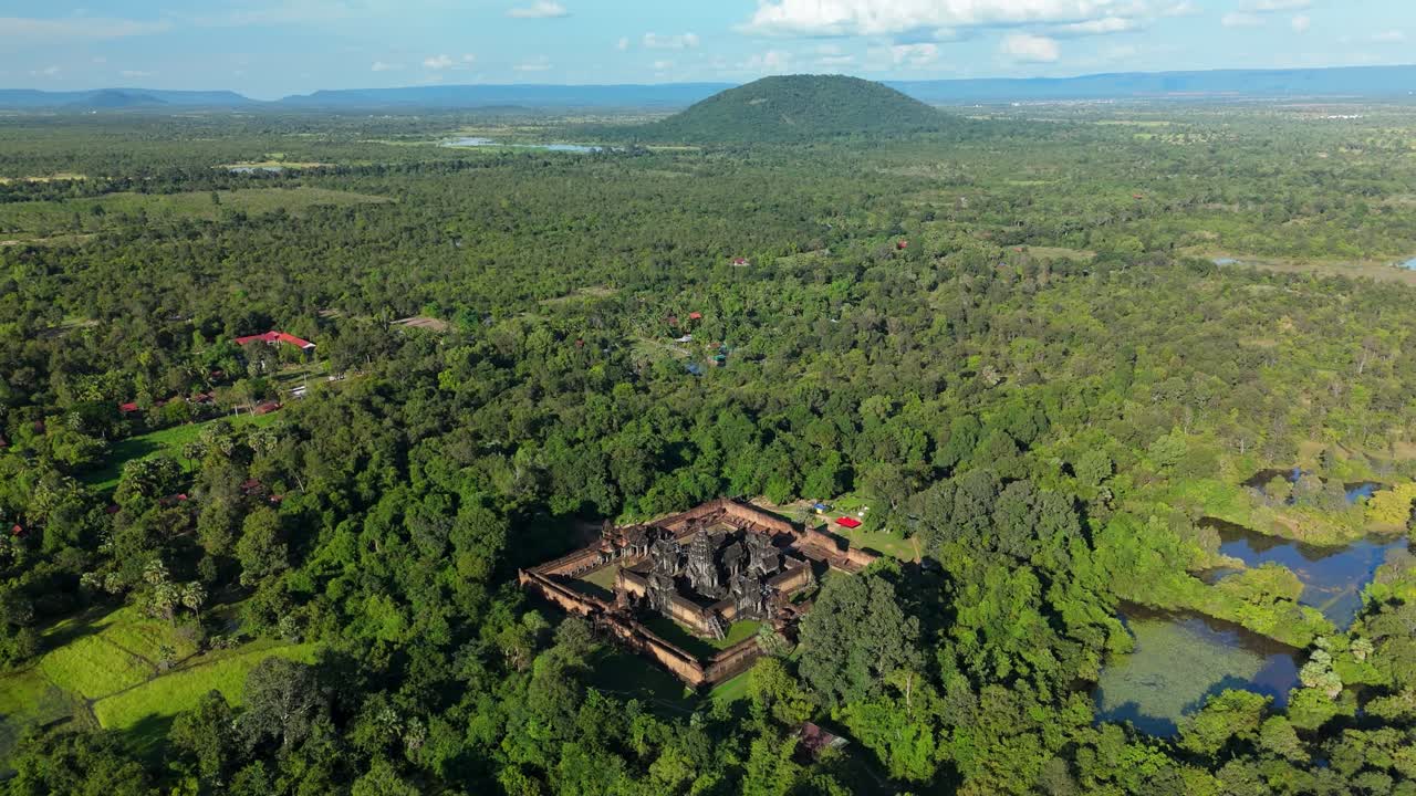 A pull-back ascending drone shot reveals Banteay Samre Temple surrounded by dense forest and wetlands in the Siem Reap