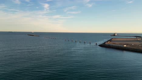 Vuelo-Con-Drone-En-El-Mar-Hasta-Un-Muelle-Viendo-Una-Parte-Que-Esta-Inutilizada-Por-Su-Antigüedad-Solo-Quedan-Los-Soportes-Y-Alguna-Plataforma-Vemos-Un-Cielo-Azul-Con-Algunas-Nubes-En-Una-Tarde-De-Invierno