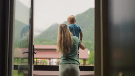 woman holds little son enjoying view of distant mountains