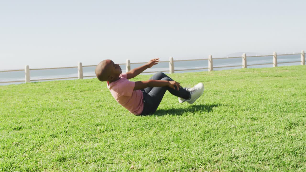 video de un feliz niño afroamericano haciendo rollos en el prado