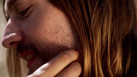 the woman is touching the man's beard as they sit together on the beach in the netherlands - close up