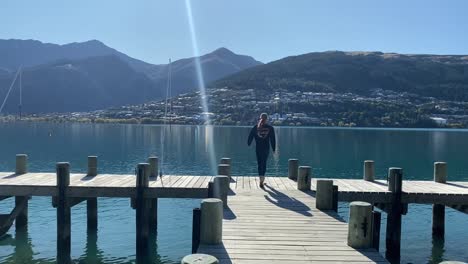 girl running along a jetty on a lake in queenstown new zealand.