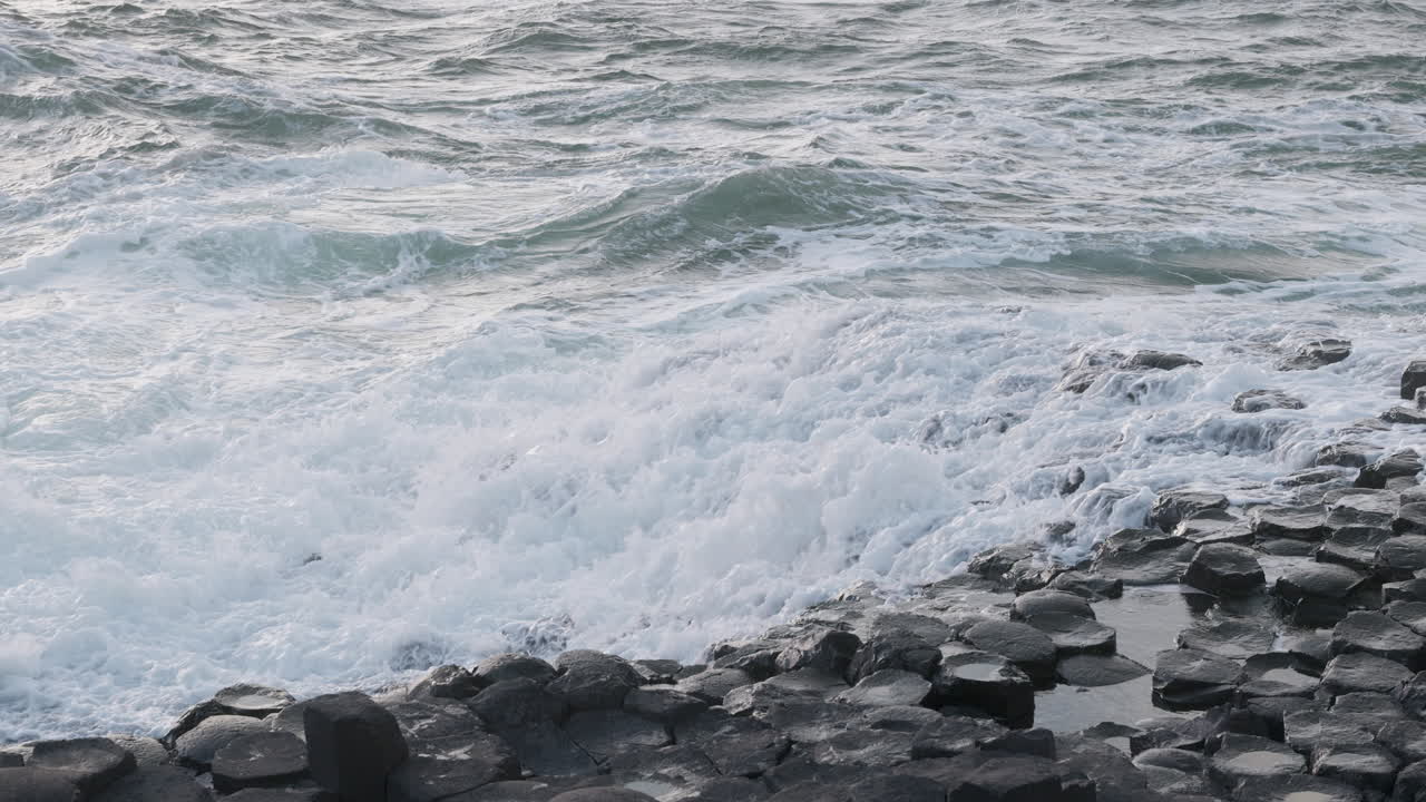 Onde al rallentatore si infrangono sulle rocce esagonali di basalto della Giant's Causeway nell'Irlanda del Nord, Regno Unito.