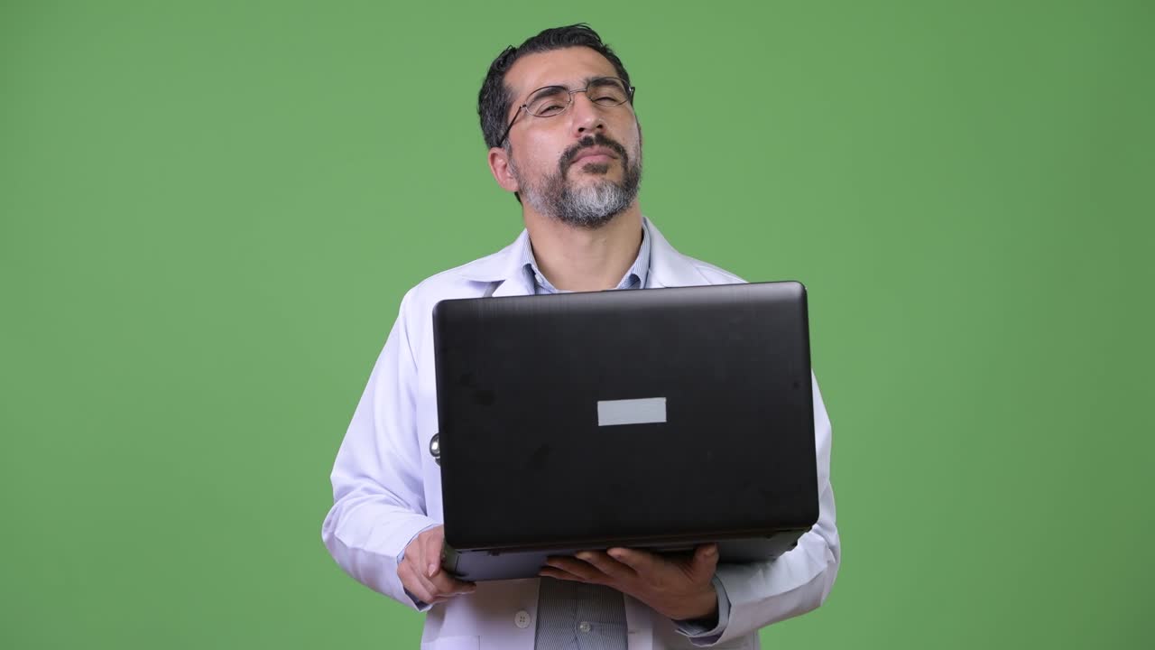 Handsome Persian bearded man doctor thinking while using laptop