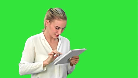 mujer de negocios de pie con una tableta digital, tocando la pantalla y sonriendo en una pantalla verde, clave de croma