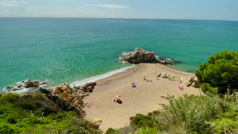 Cala-Roca-Grossa-Día-Soleado-De-Verano-Mediterráneo-Europeo-Turismo-Paraíso-Playa-Vista-Aérea-Desde-Drone-Contraste-Con-Roca-Arena-Y-árboles-Verdes-Barcelona-España-Costa-Brava