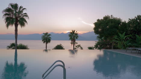 Outdoor-swimming-pool-on-resort-near-the-sea-scene-at-sunset