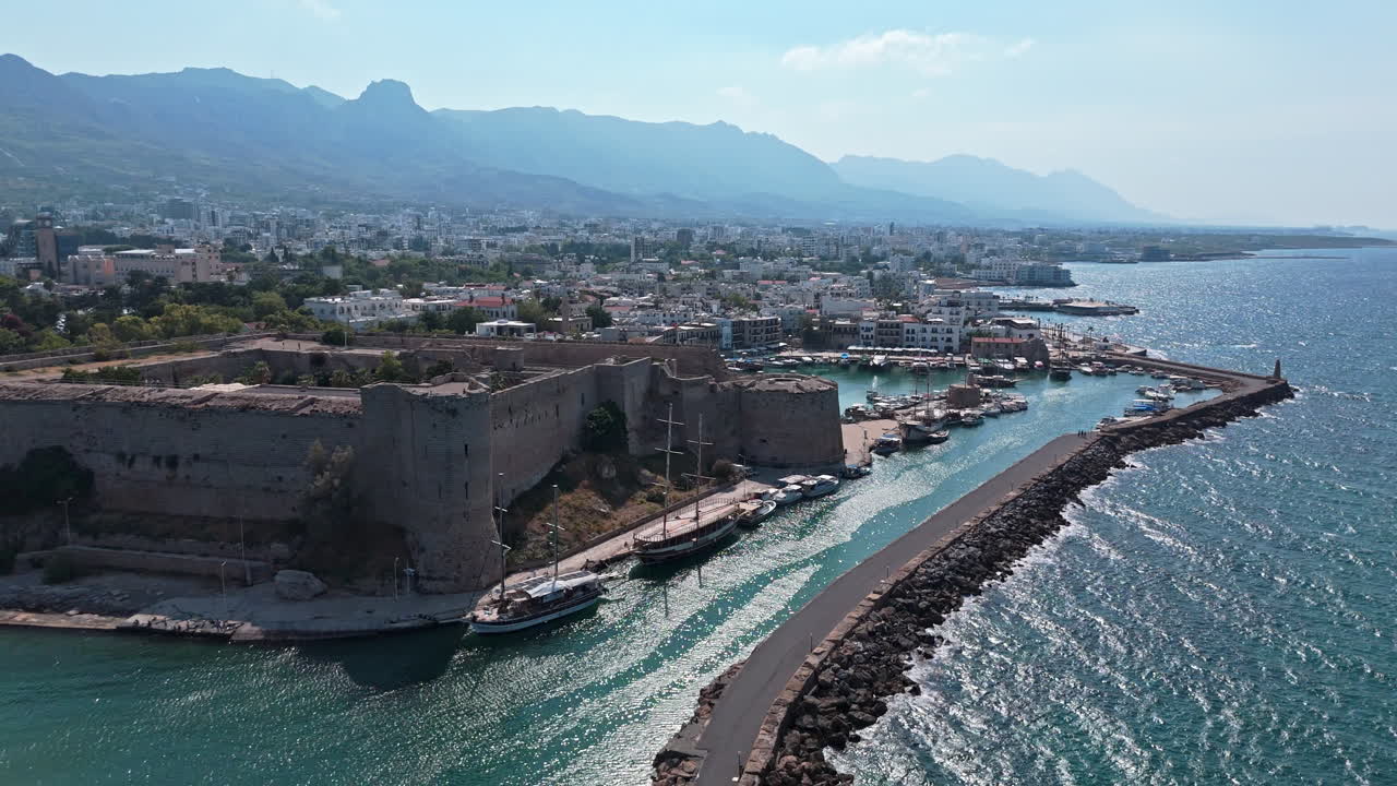Kyrenia harbor and castle with mountains and coastline in the background, aerial view