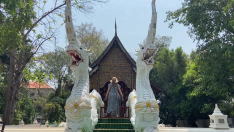 Female-tourist-with-hat-walking-in-Thai-temple,-Chiang-Mai