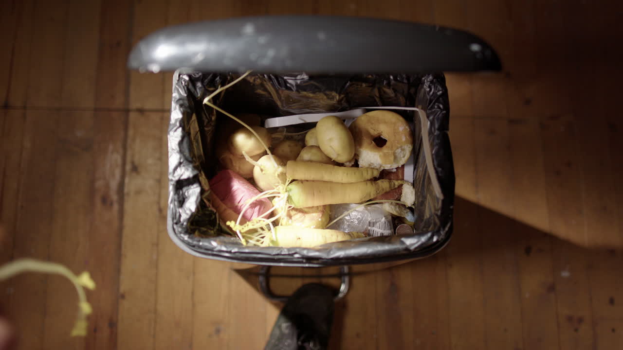 만료 된 채소 의 부분 이 검은색 쓰레기통 에 던져지고 있다