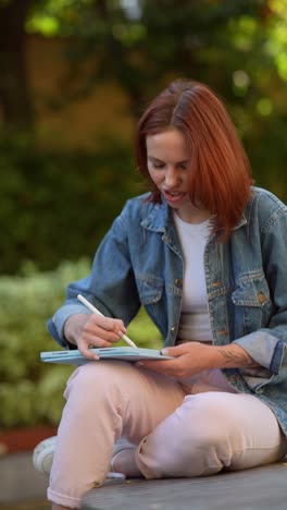 woman drawing on tablet in a park