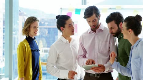 Smiling-business-team-discussing-over-digital-tablet