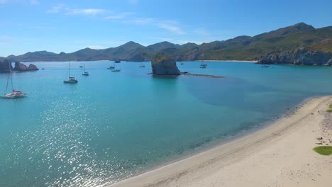 overlooking a protected bay of sailing yachts anchorage near a white sand beach surrounded by small mountains of the coast of san juanico, mexico, baja california sur