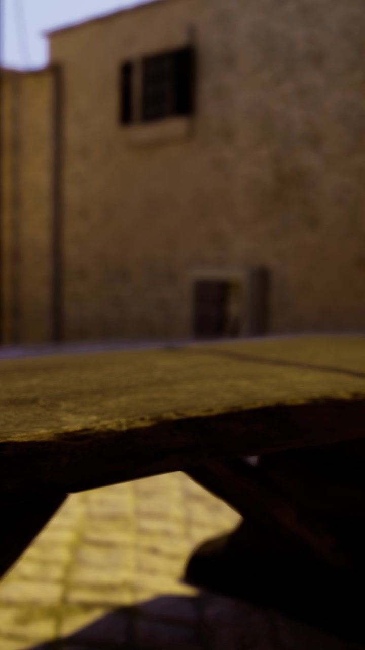 Tavolo di legno in un cortile con muro in pietra alla luce della sera fuori da un ristorante.