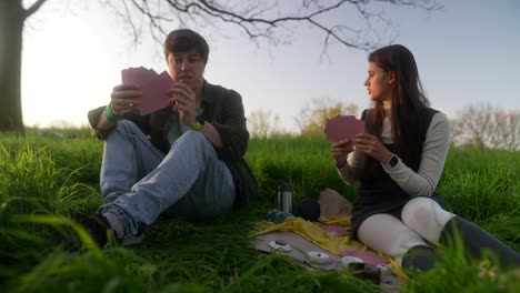 couple playing cards in a park at sunset