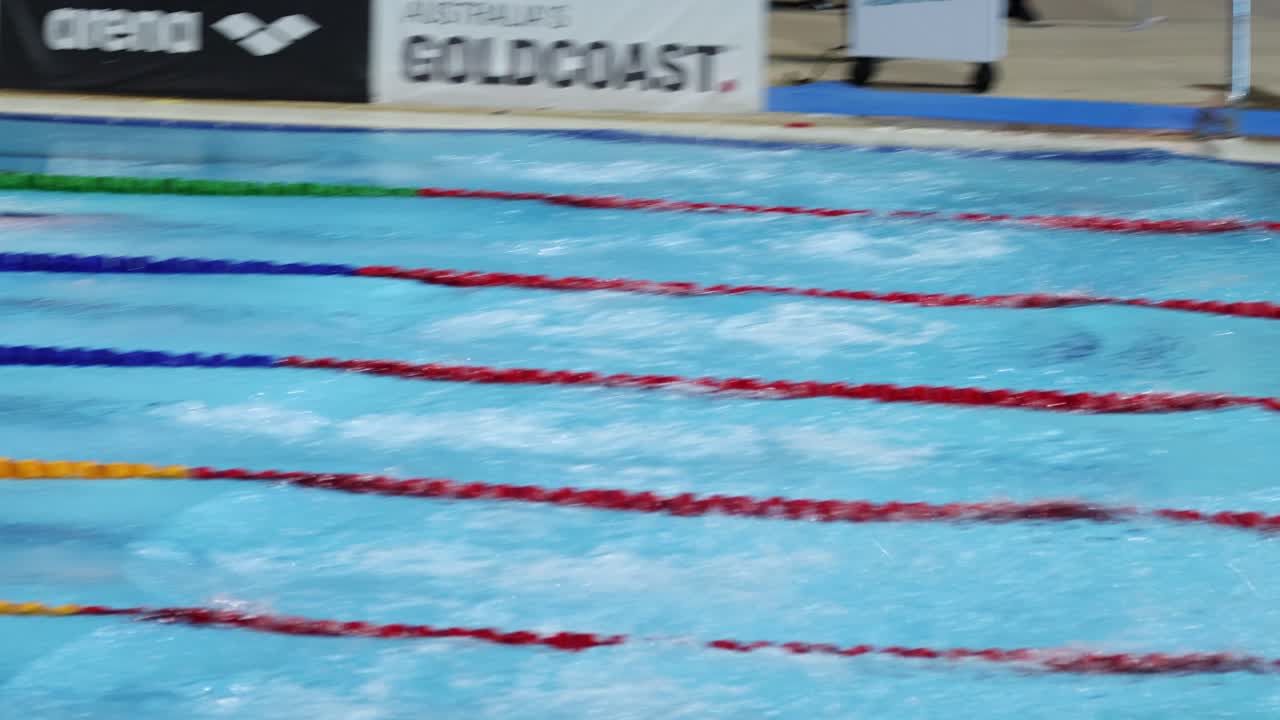 Nadadores mergulham e competem numa piscina de várias raias