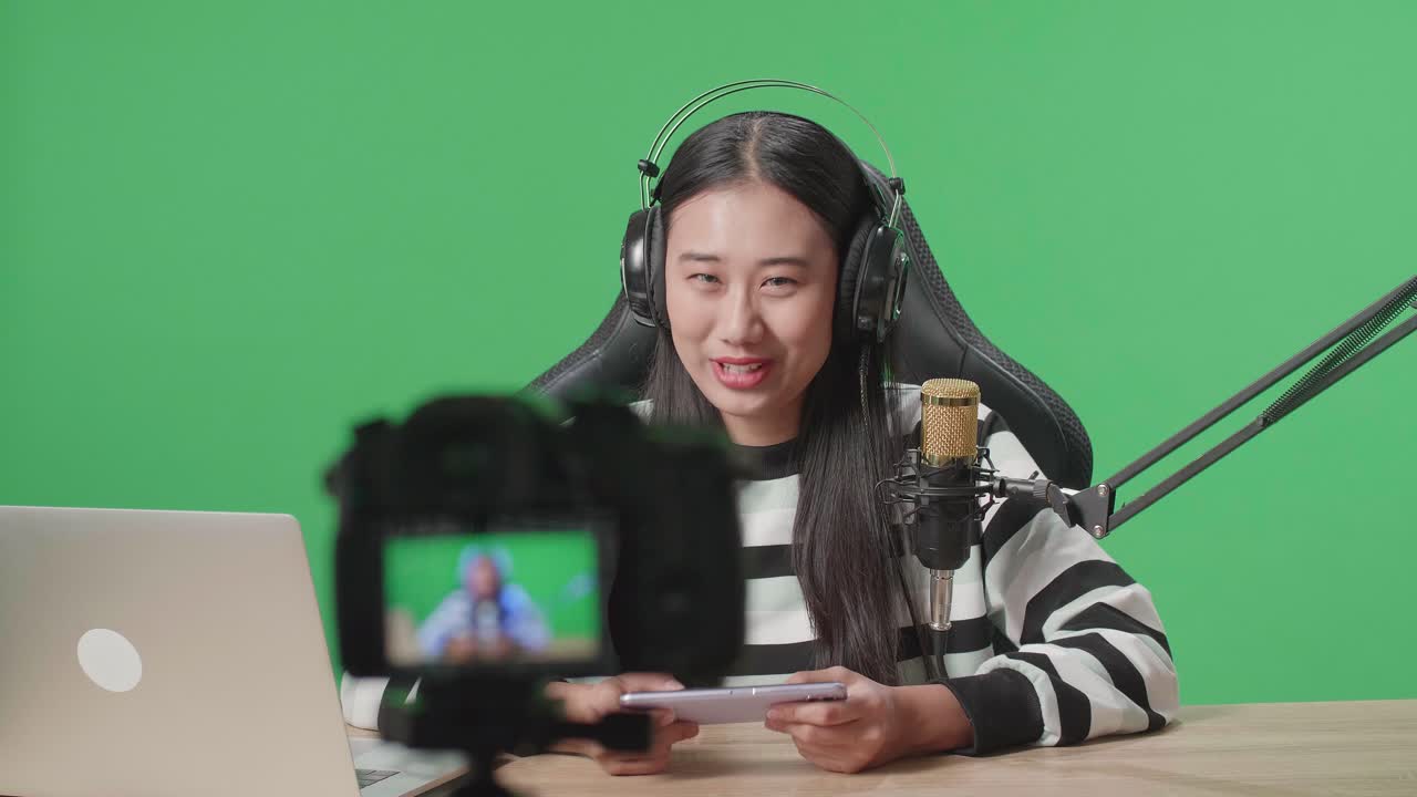 Donna in live streaming di un gioco mobile su schermo verde