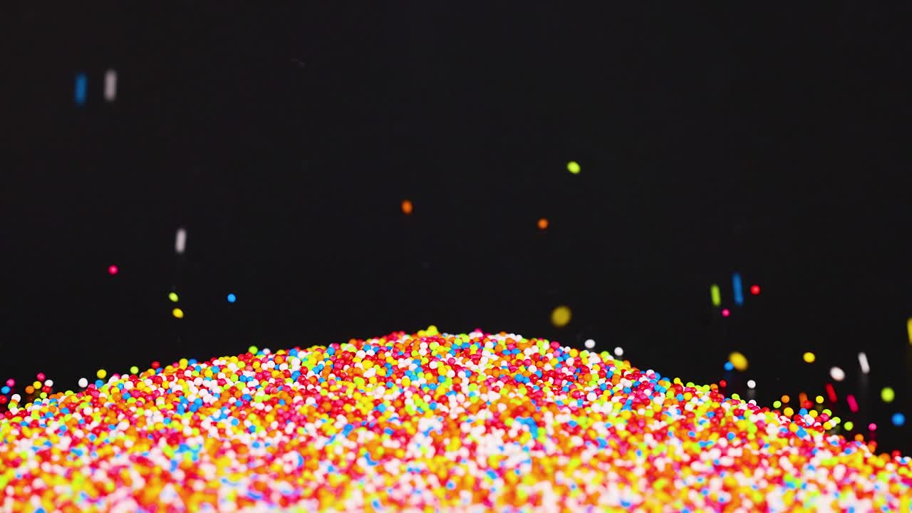 Vibrant sprinkles cascade onto a growing pile