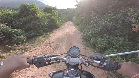 biker riding offroad in a dense green alley riding to the mountain at parasnath hill in jharkhand, india