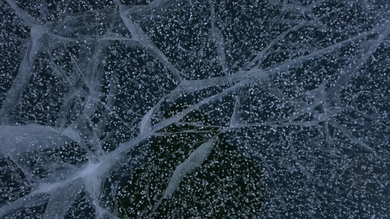 Ghiaccio unico e congelato con crepe di bolle d'aria sui Laghi Smeraldo e dei Sogni, Parco Nazionale delle Montagne Rocciose (RMNP), Colorado. Veduta aerea da drone sotto un cielo blu e soleggiato in un freddo inverno alpino, con neve spazzata dal vento sul sentiero di Bear Lake. Panoramica.