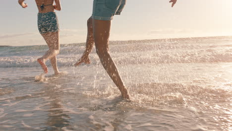 girl friends on beach splashing sea water at each other having fun playing game on warm summer day by the ocean enjoying summertime holiday vacation