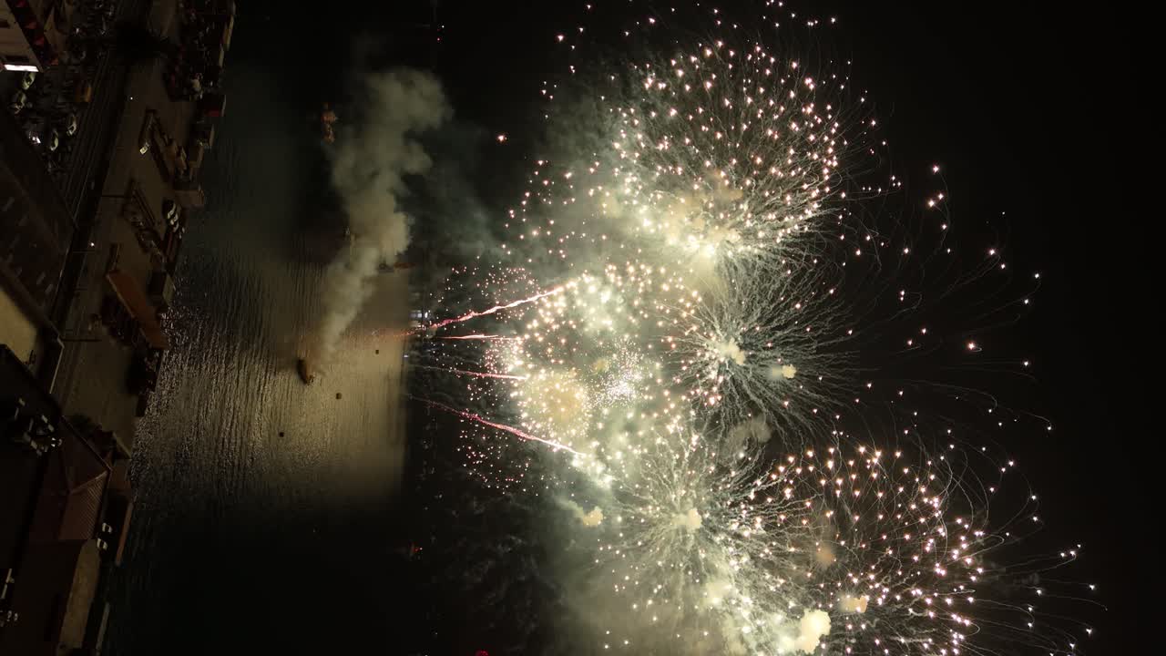 Flyover vertical view of a ship launching coordinated fireworks on New Year's Eve 2023 in Valparaiso Chile