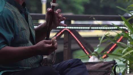 a man playing a tro, a cambodian stringed instrument