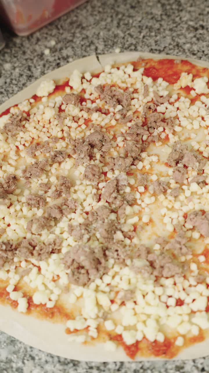 Preparazione della pizza con condimenti