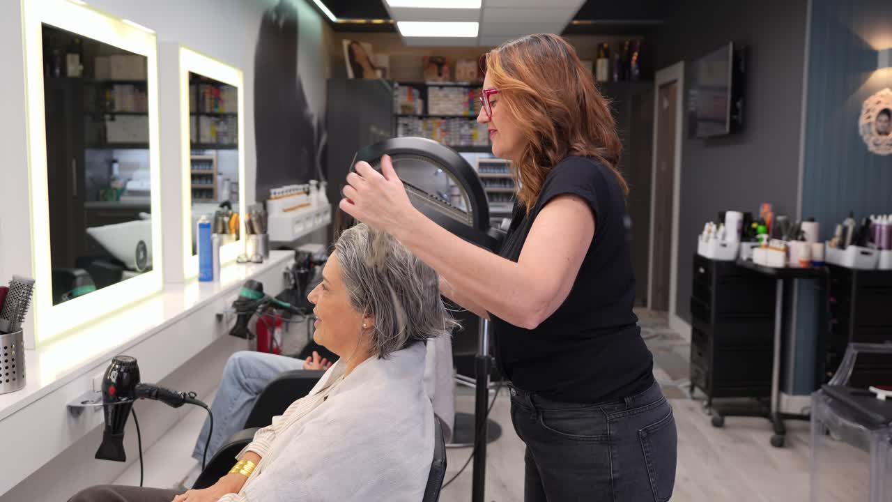 Cabeleireiro aplicando produto para cabelo em senhora em salão moderno