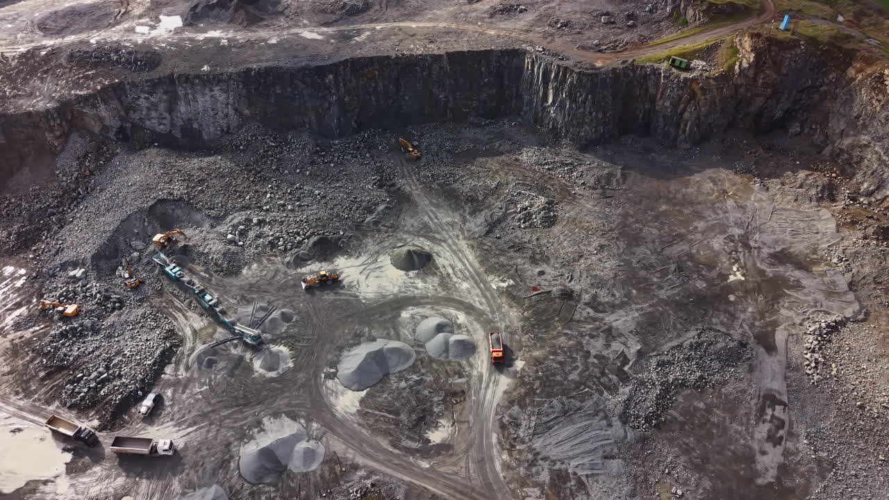 Granite quarry shows workers extracting stone and operating heavy equipment during daylight hours