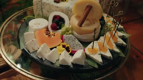 gourmet cheese board with assorted cheeses tropical fruits and edible flowers on dark plate