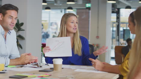 colleagues applauding as businesswoman gives presentation in modern open plan office