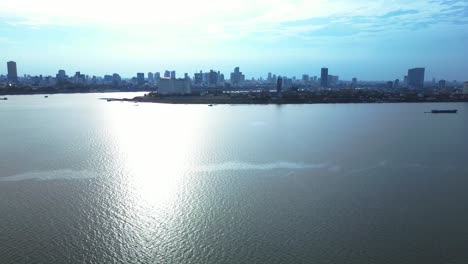 cargo ship sailing on the mekong river near phnom penh skyline in cambodia. marvelous aerial view flight rotation to left drone