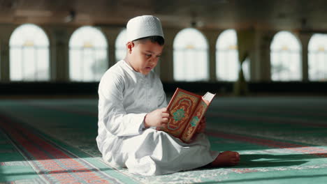 islam, boy in mosque reading quran for learning