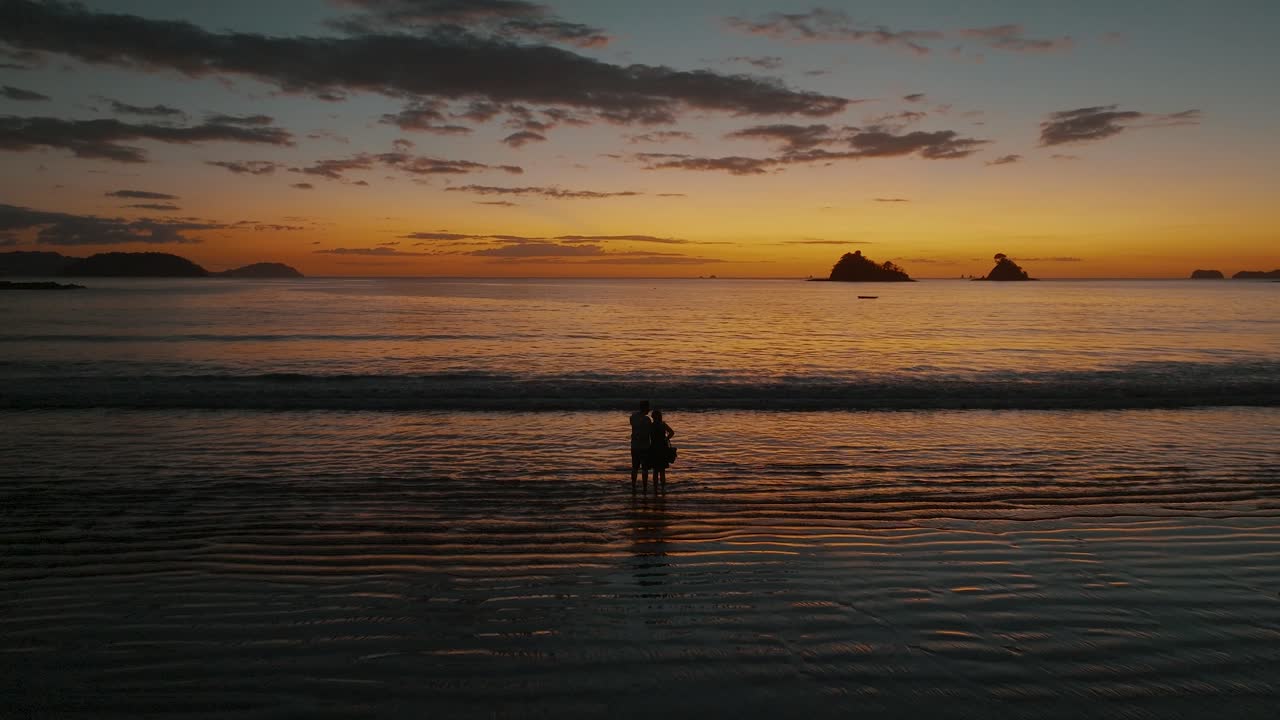 해질녘 해변에 서 있는 커플의 실루엣 - 와이드