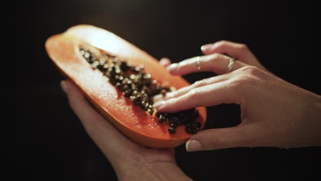 Weibliche-Hände-Halten-Frische,-Saftige-Papaya,-Halbiert