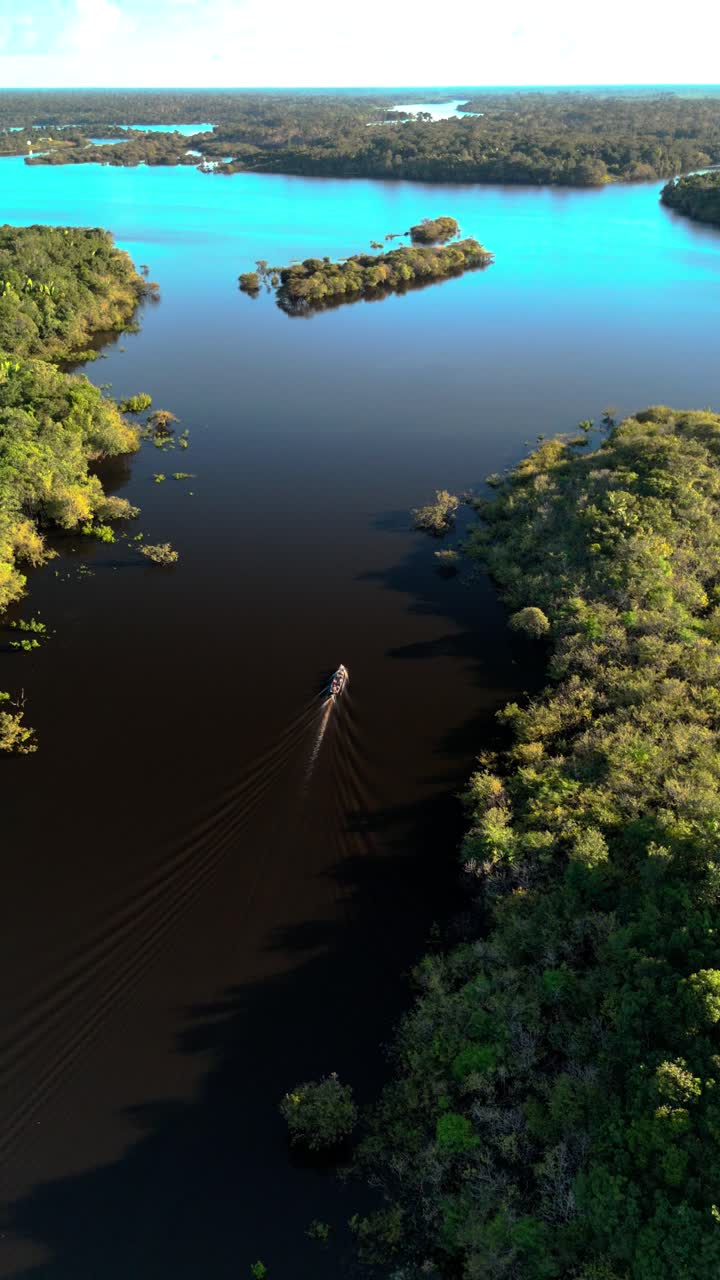 Vertical: Drone closes in on boat on Juma River in the Amazon, surrounded by jungle