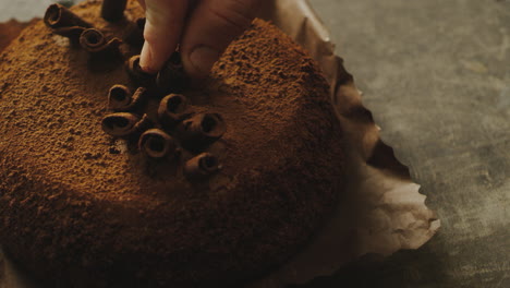 Closeup-woman-hand-decorating-cake-with-chocolate-shavings-in-slow-motion.