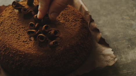 closeup woman hand decorating cake with chocolate shavings in slow motion.