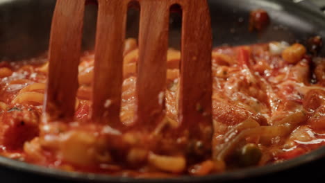 stirring pasta with sauce