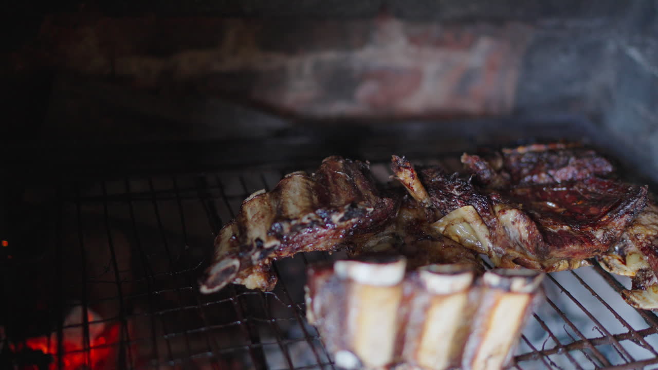 Extreme close up of sizzling beef ribs on traditional Argentine barbecue grill, camera slides over juicy bones, smoky texture, charred meat, authentic asado atmosphere, wood-fired embers, slow motion.
