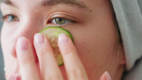 bright close-up view of woman placing a cucumber slice on her eyes while relaxing, she enjoys a soothing skincare ritual with cucumber slices for a refreshing facial treatment